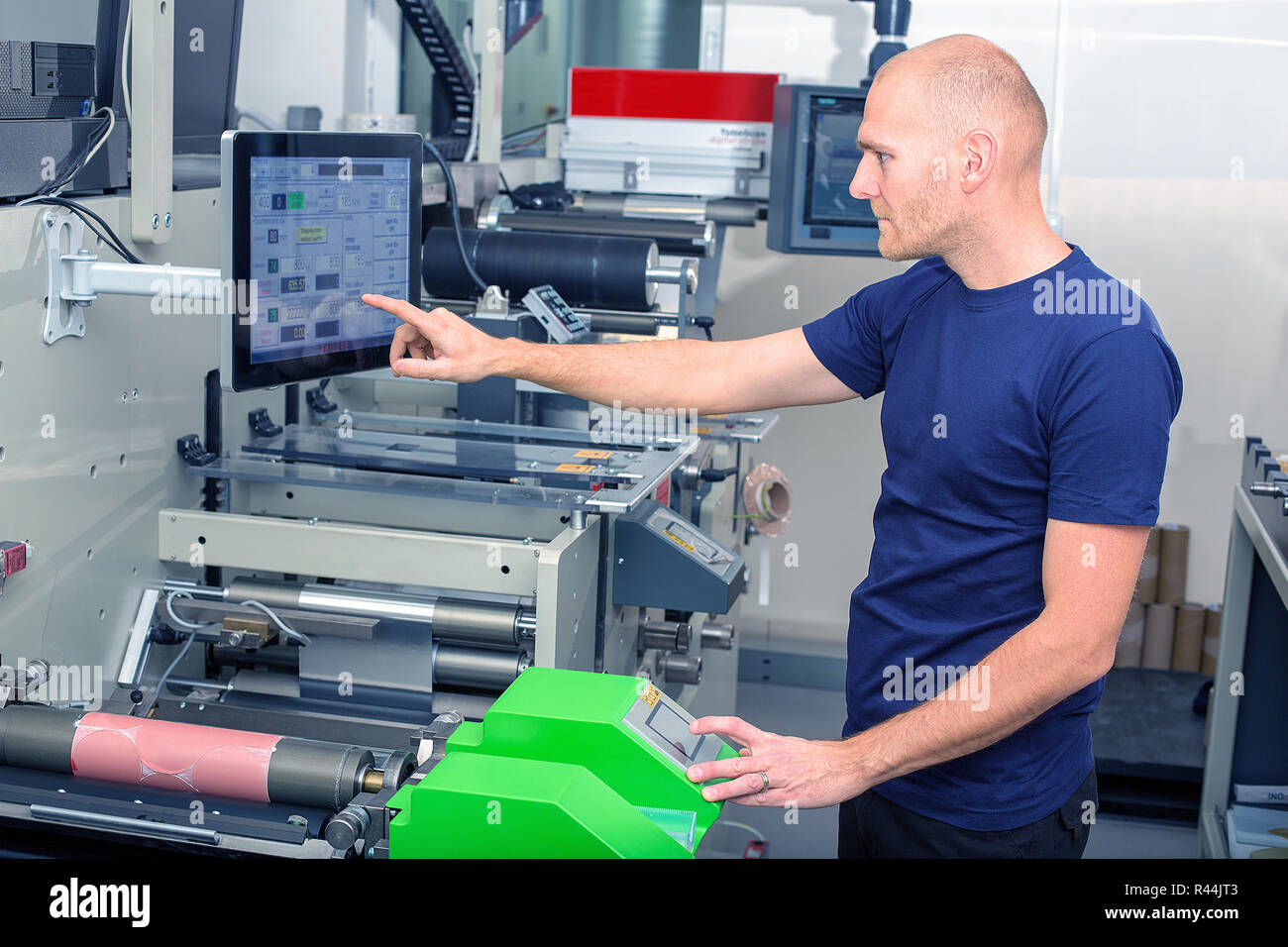 Arbeitnehmer neben der Druckmaschine die Daten, indem Sie den Touchscreen. Qualifizierte drucken Bedienelemente Druckmaschine über Touchscreen Stockfoto