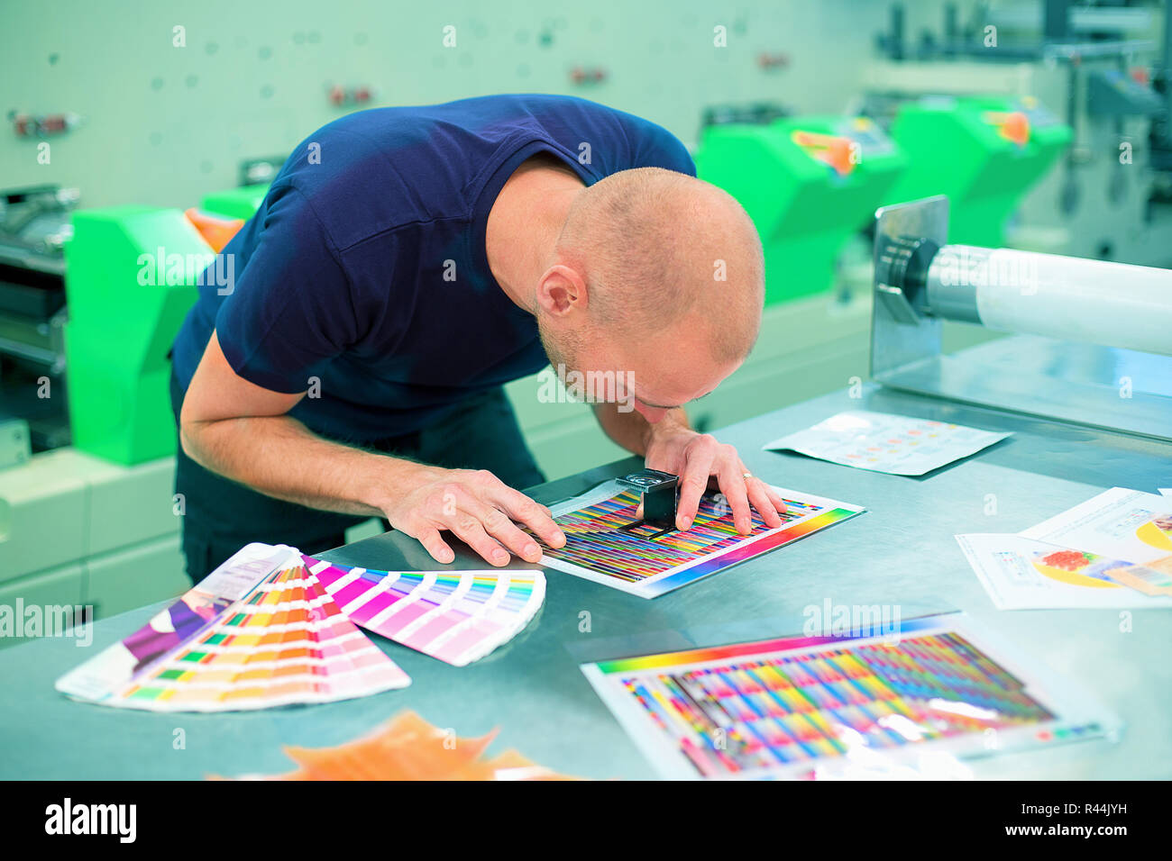 Arbeiter in einer drucken, und drücken Sie Mitte verwendet eine Lupe, um die Druckqualität zu überprüfen. Szene, die Druckqualität prüfen. Stockfoto