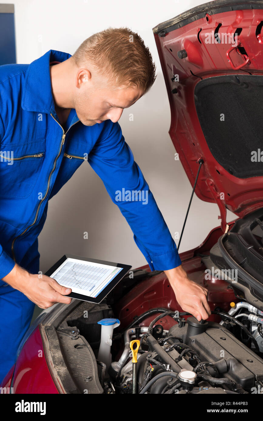 Mechaniker mit digitalen Tablet während der Prüfung Auto Motor Stockfoto
