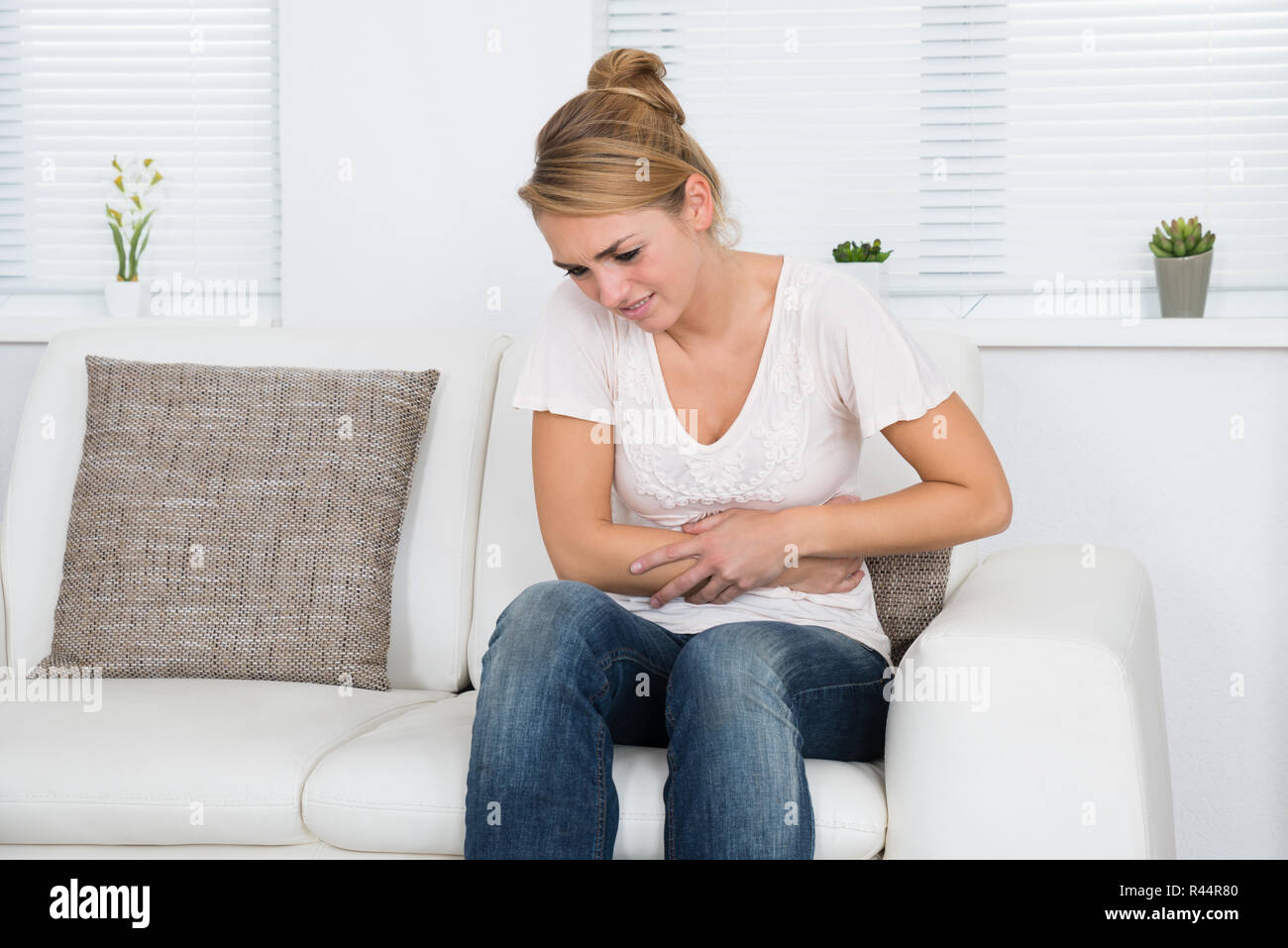 Frau mit Magenschmerzen beim Sitzen auf dem Sofa Stockfoto