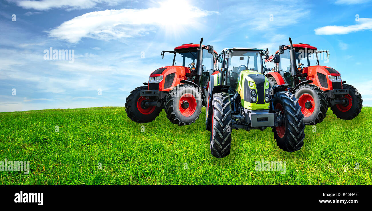 Landwirtschaftliche Werbebanner - Gruppe der neuen und modernen generischen Traktoren auf der grünen Wiese im sonnigen Tag (gemischt). Stockfoto