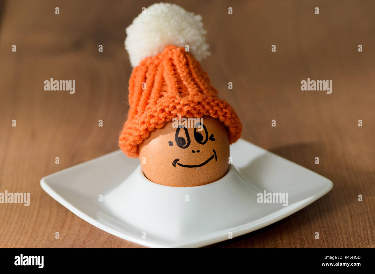 Lächelnde Ei mit gestrickten Motorhaube sitzt im Weißen eggcup Stockfoto