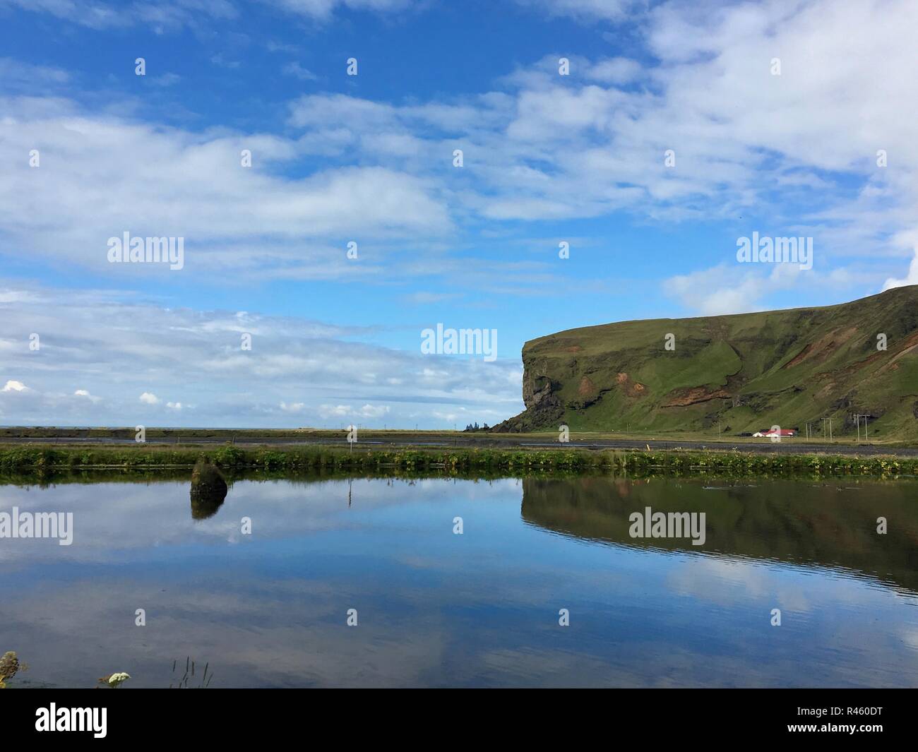 Eine ruhige See mit Reflexion von Cliff und Sky Stockfoto