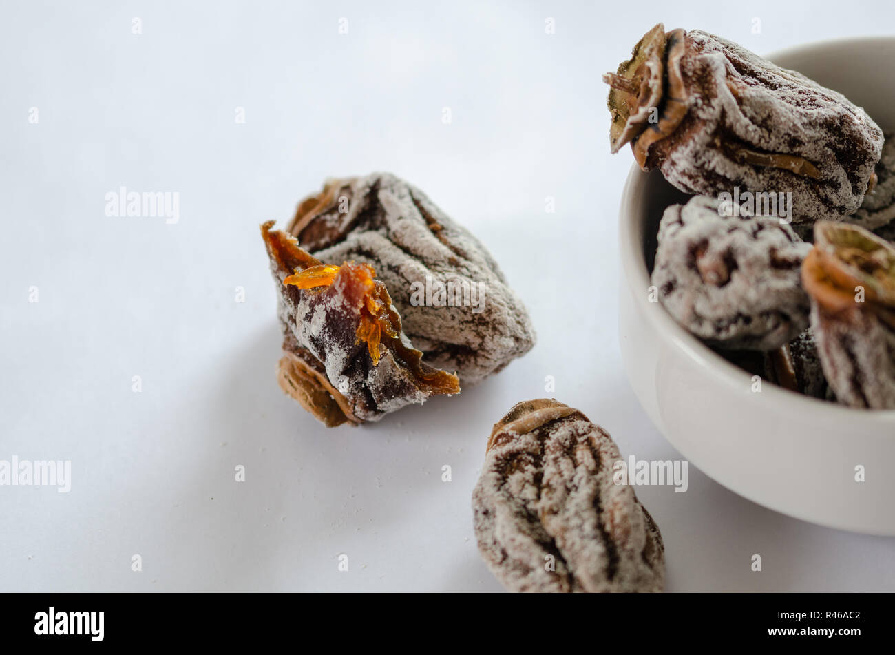 Ein paar getrocknete Kaki in eine Schüssel und einen Bissen auf einem weißen Hintergrund. Stockfoto