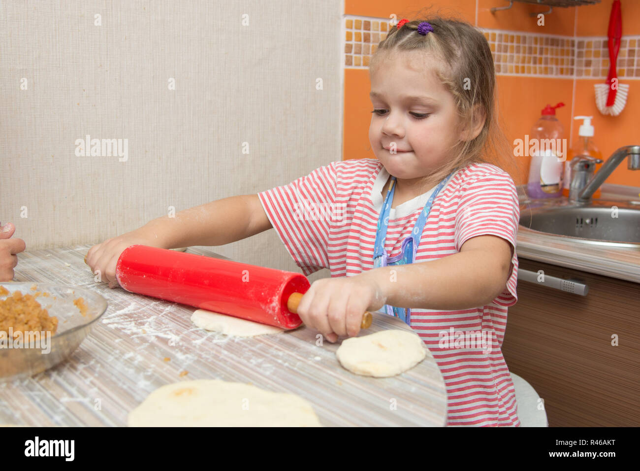 Girl hart rollt Nudelholz Pfannkuchen Teig für Kuchen Stockfoto