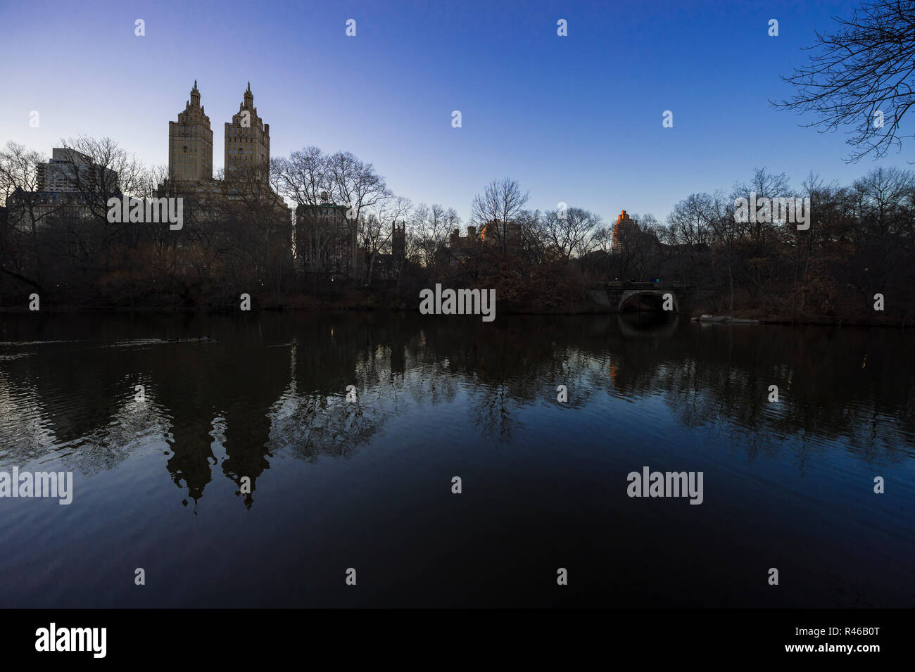 Ruhige Szene von winter bäume mit der Skyline Silhouette der Upper West Side in den ruhigen Wasser des Central Park See in New York spiegeln Stockfoto