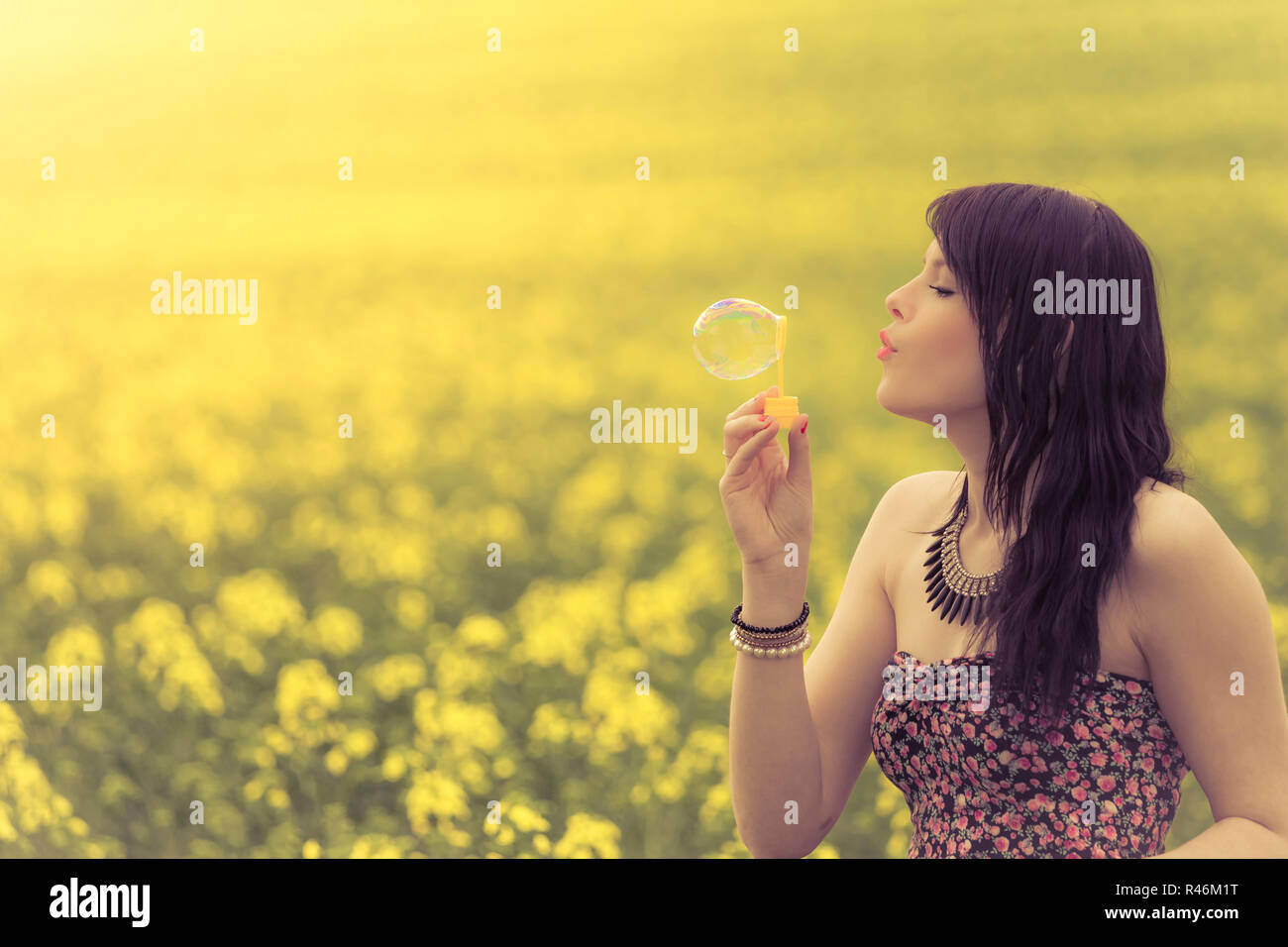Schöne Frau weht eine Seifenblase im Sommer Natur Stockfoto