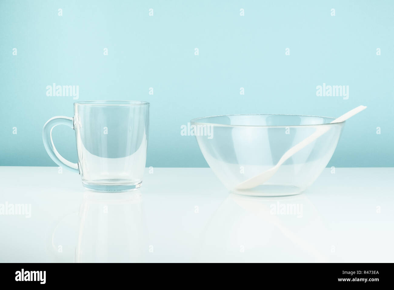 Leere Glas Schüssel und Becher auf den Tisch. Hunger oder Diät Konzept: Sauber transparrent Geschirr in weißen und blauen Hintergrund Stockfoto