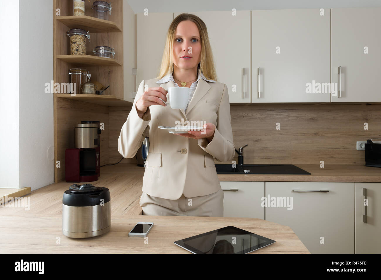 Kaukasische Frau in Business Suite trinken Kaffee in der Küche Stockfoto