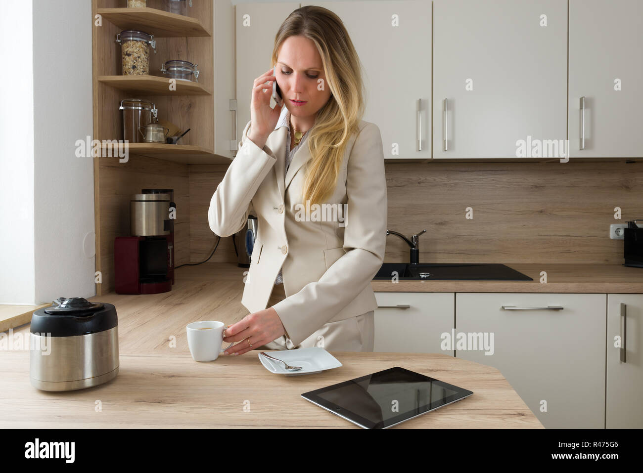 Moderne Geschäftsfrau mit Smartphone und Kaffee in der Küche Stockfoto