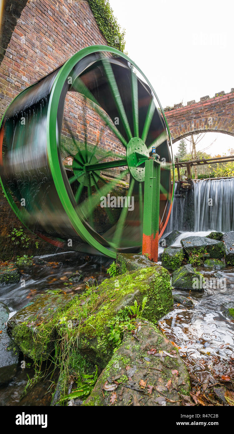 Porträt Aufnahme eines sich bewegenden traditionelle Wassermühle Rad von Wasserfällen im Hintergrund geliefert, auf einem kalten Herbst morgen in Thüringen. Stockfoto