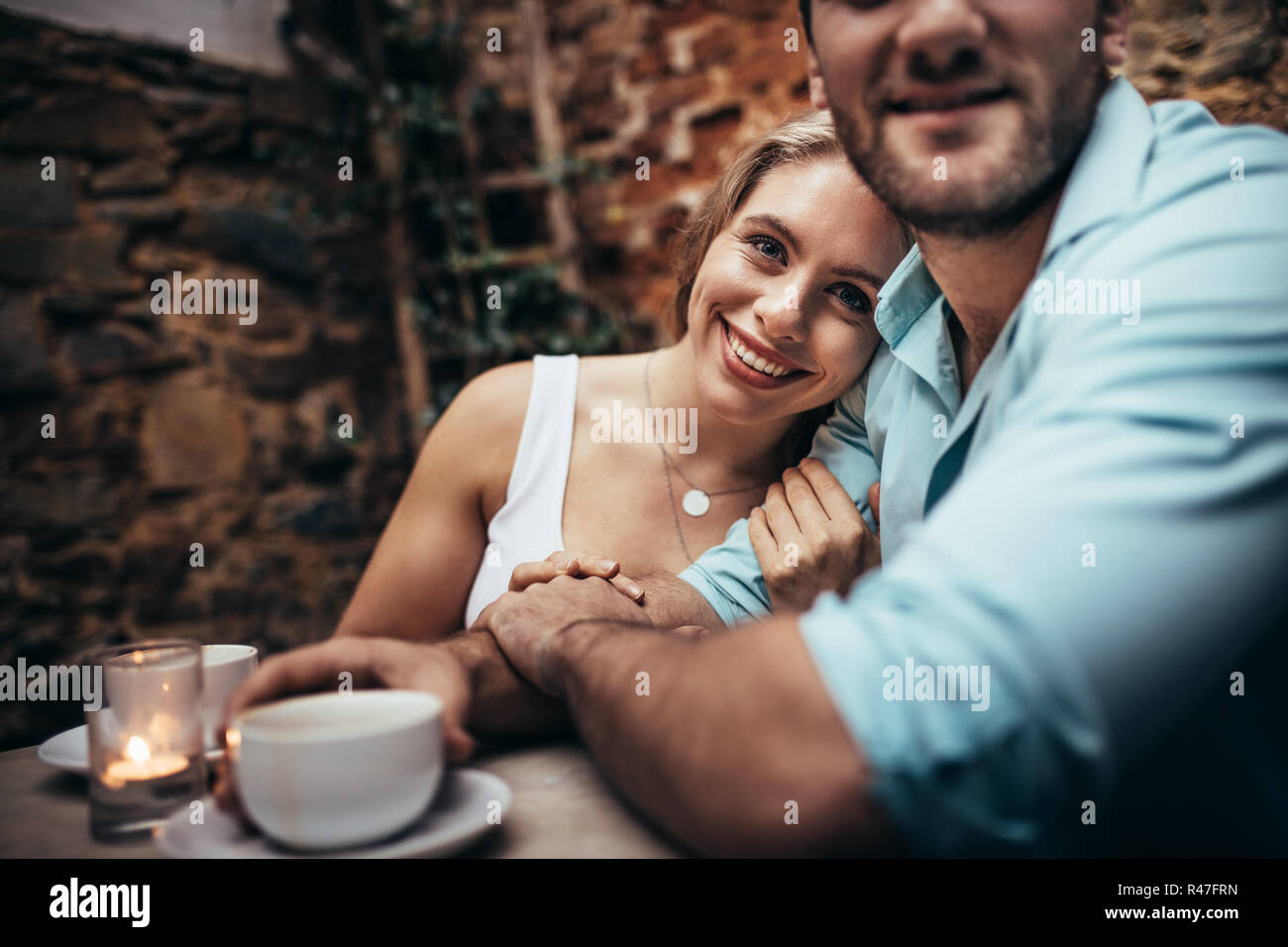 Lächelnde Frau sitzt mit ihrem Freund in einem Restaurant hielt seinen Arm. Paar zusammen in einem Café die Zeit zusammen zu sitzen. Stockfoto