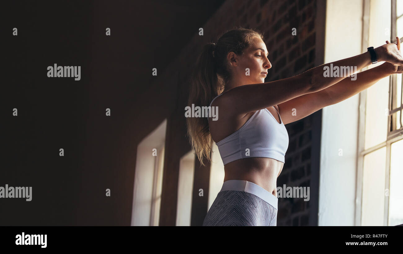 Gesunde Frau im Sport Kleidung zu tun Stretching Übungen im Fitnessstudio in der Nähe der Fenster. Weibliche Aufwärmen für Training im Fitnessraum. Stockfoto