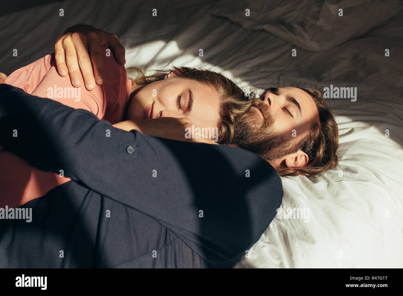 Paar liegend auf Bett zusammen mit geschlossenen Augen. Frau schlafen auf den Arm ihres Mannes im Bett mit Sonne einfallende Licht vom Fenster. Stockfoto
