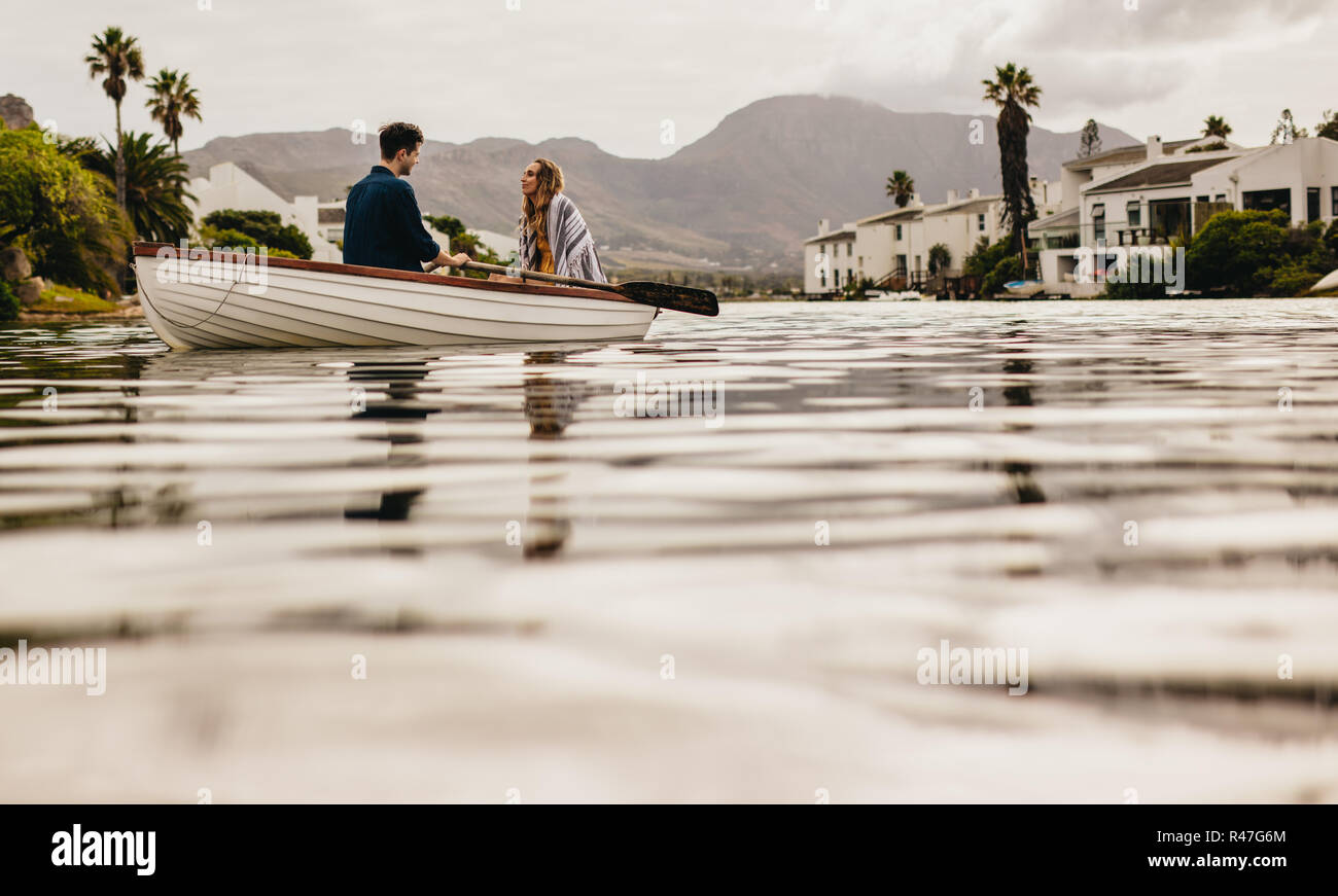 Low Angle View von ein Paar in einem Boot zu sitzen und zu reden. Paar in Liebe auf einem Boot Datum zusammen sitzen, rudern mit dem Boot. Stockfoto