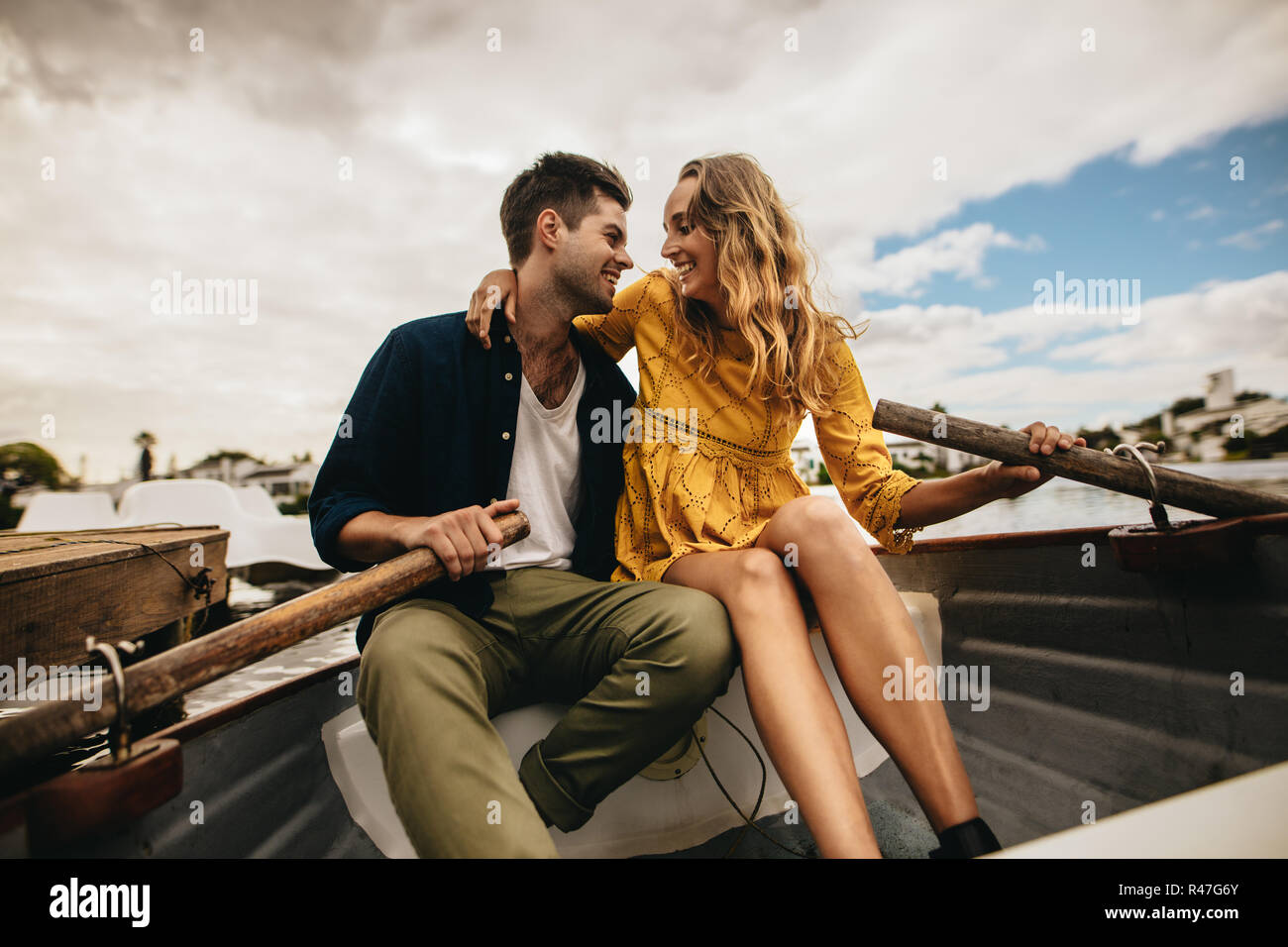 Romantisches Paar auf einem Datum sitzen gemeinsam in einem Boot an einander suchen und lächelnd. Lächelndes Paar sitzen in einem Boot halten die Paddel auf einem Roma Stockfoto