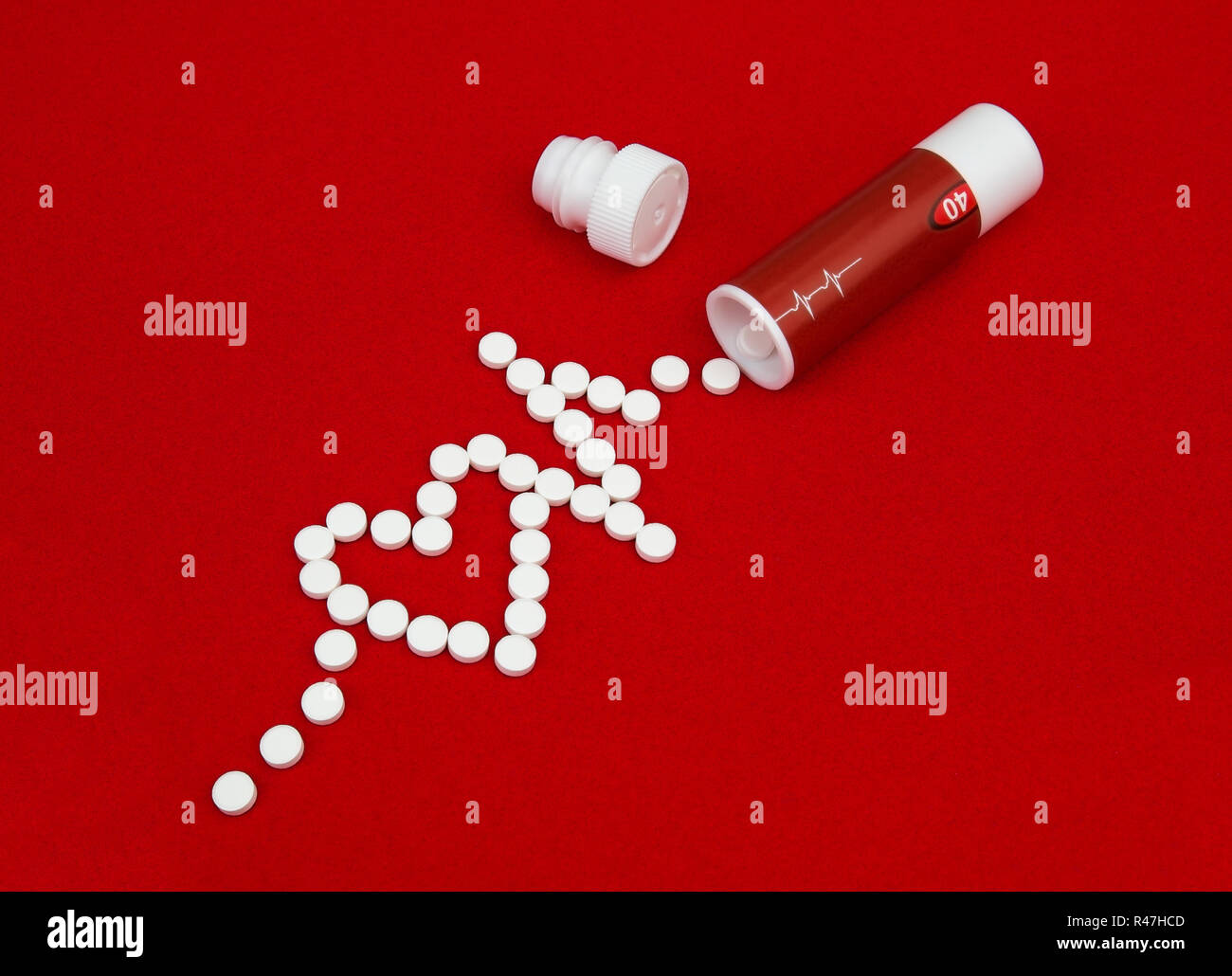 Pillen von Herzkrankheit gegossen aus der Box auf rotem Samt. Die Tabletten in der Form eines Herzens und eines sinusförmigen verstreut. Stockfoto