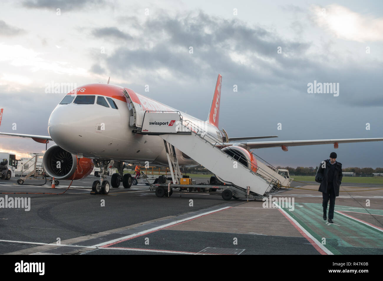 Einsame männliche Beifahrer Aussteigen einen Easyjet Flug 319 Flugzeuge in Belfast International Airport an einem kalten grauen bewölkten Herbst Tag. Stockfoto