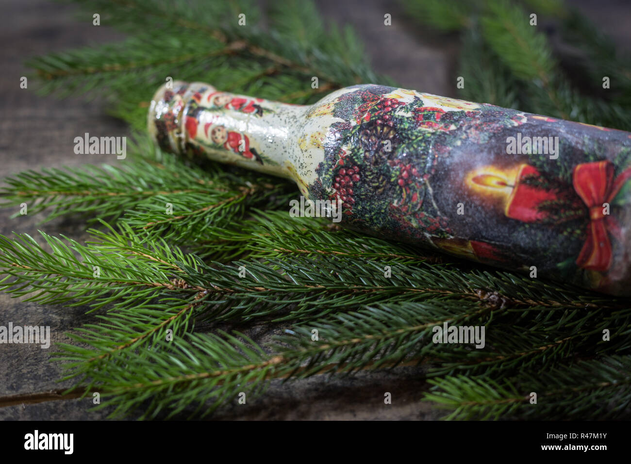 Flasche mit Decoupage Technik mit weihnachtlichen Motiven und Tannenzweigen auf einer hölzernen Hintergrund eingerichtet. Begriff der traditionellen Weihnachtsfeier. Stockfoto