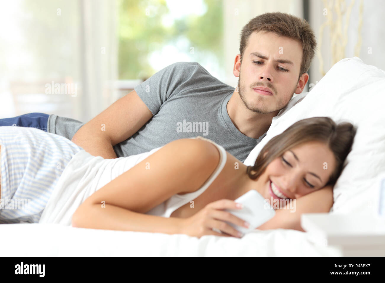 Eifersüchtig klatsch Mann seine Frau Handy beobachten Stockfoto