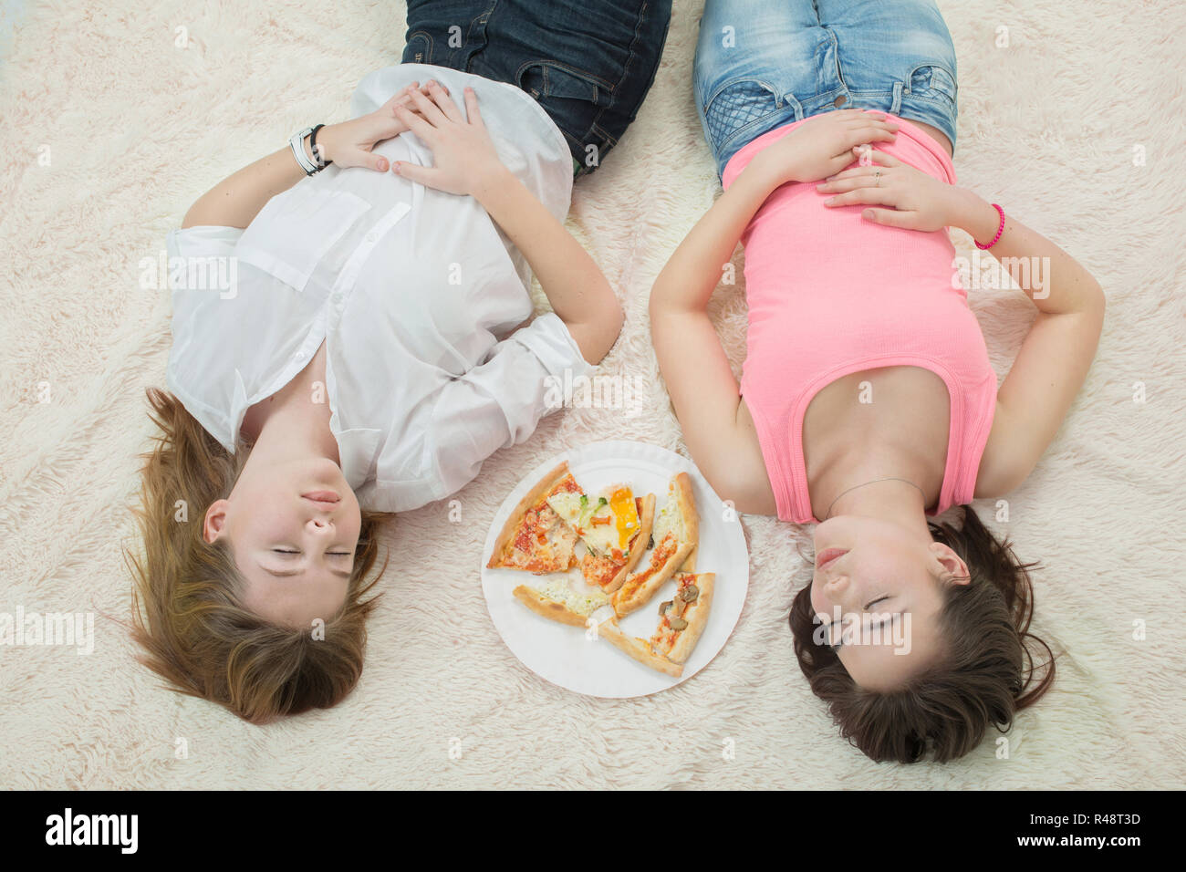 Traurig überessen Mädchen lügen Träumen mit Pizza Stücke auf weißem Hintergrund Stockfoto