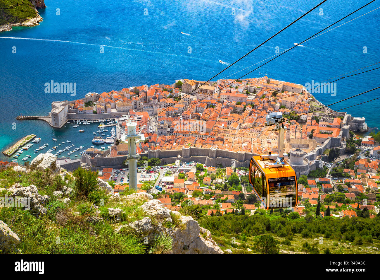 Antenne Panoramablick auf die Altstadt von Dubrovnik mit dem berühmten Cable Car über Srd Berg an einem sonnigen Tag mit blauen Himmel und Wolken im Sommer, Dalmatien, Stockfoto