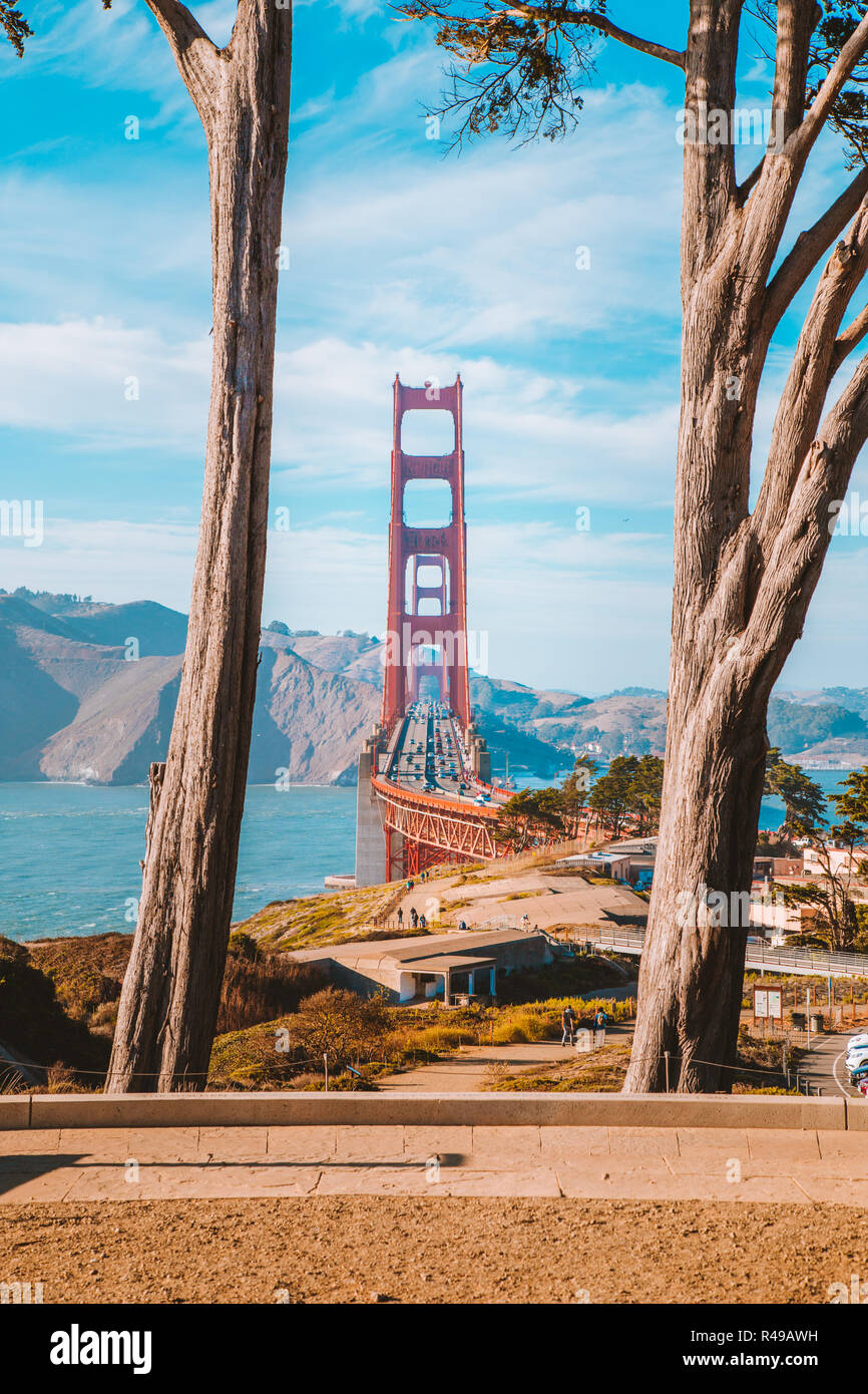 Berühmte Golden Gate Bridge von alten Zypressen bei Scenic Presidio Park gerahmt an einem schönen sonnigen Tag mit blauen Himmel und Wolken, San Francisco, USA Stockfoto