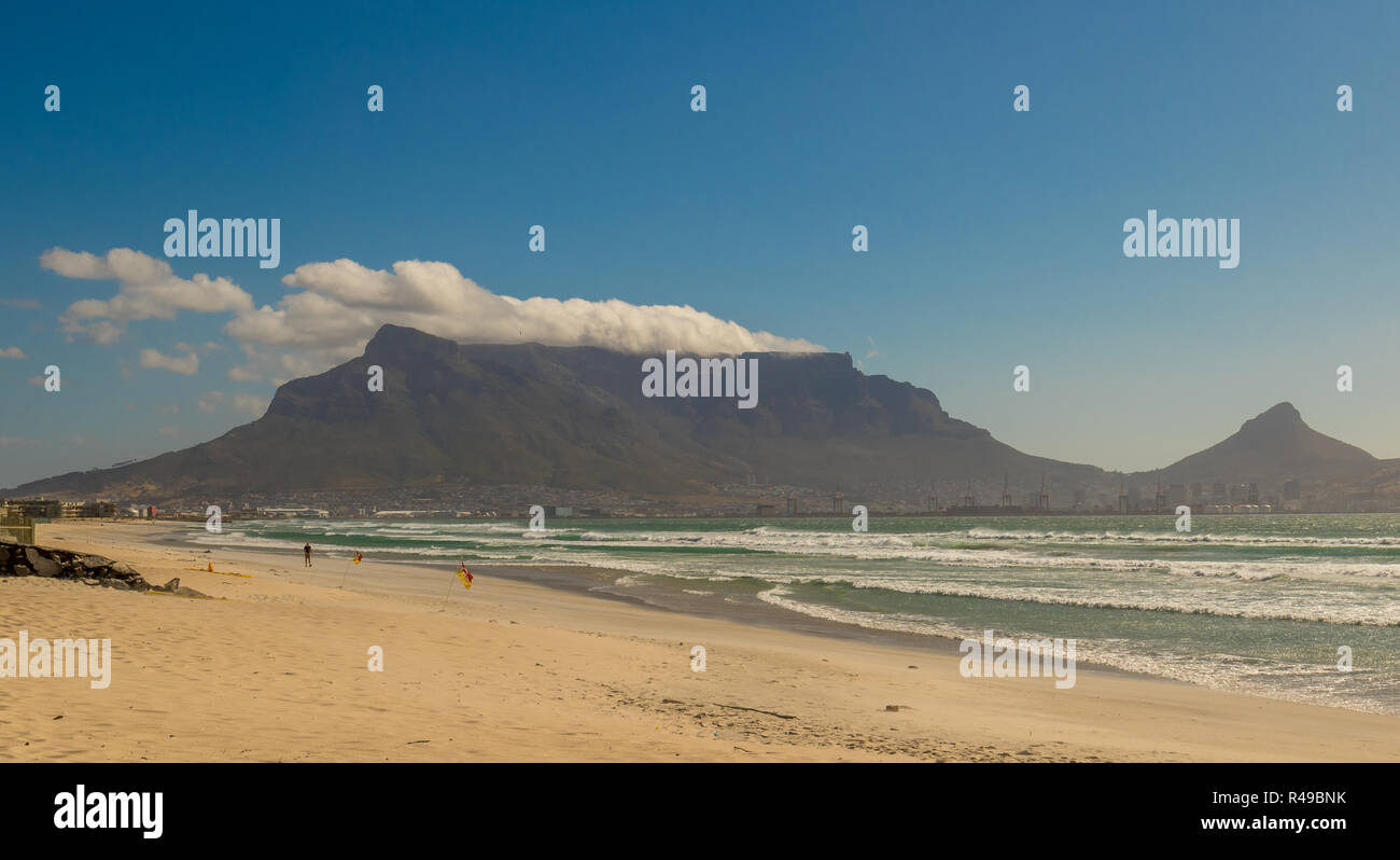 Kapstadt, Südafrika - ein nicht identifizierter beachgoer auf Milnerton Beach an einem windigen Tag mit dem Tafelberg im Hintergrund Stockfoto