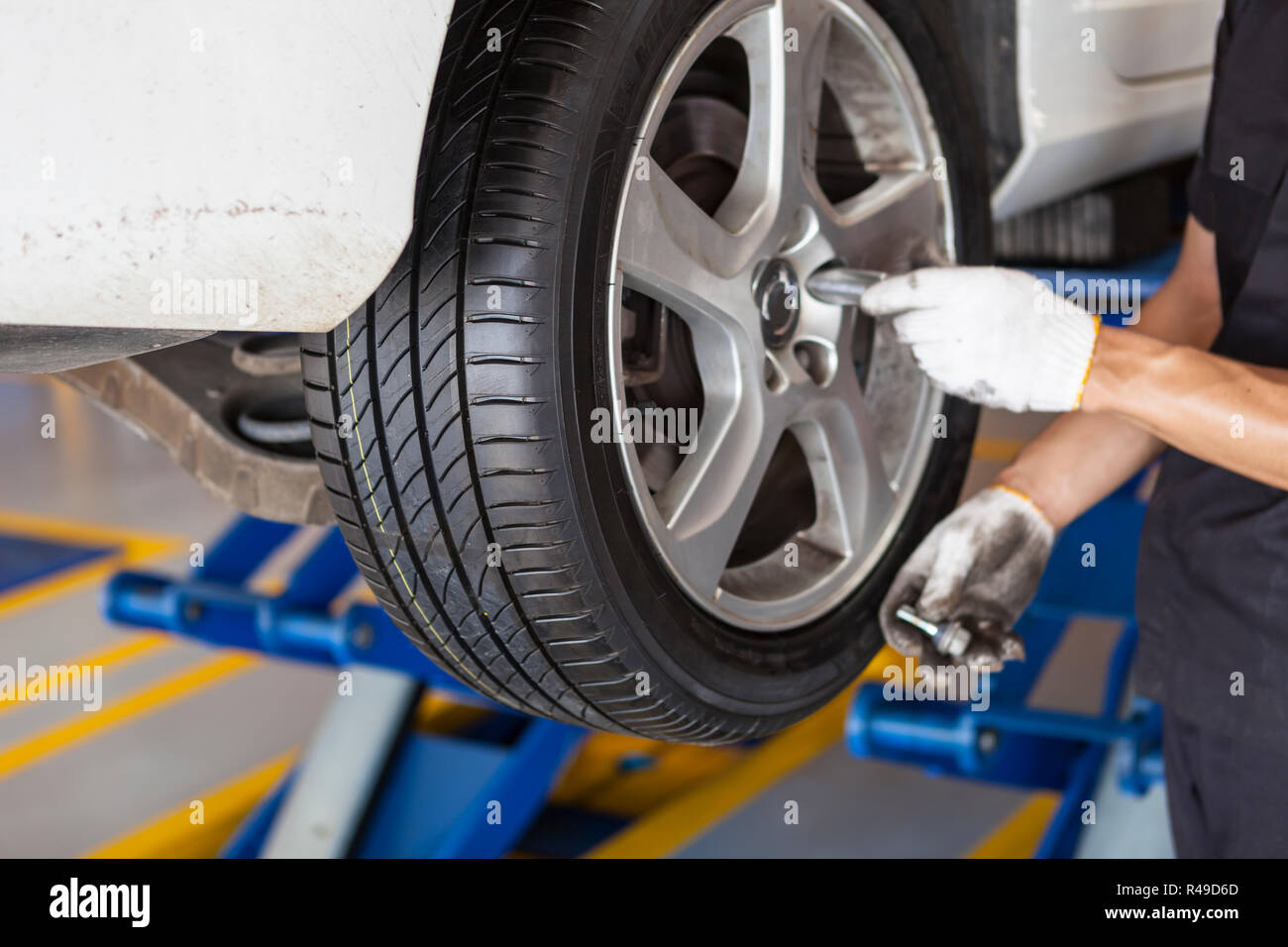 Auto Rad Reifen auf die scissor Krane durch die Hände der Mechaniker in der Garage Stockfoto