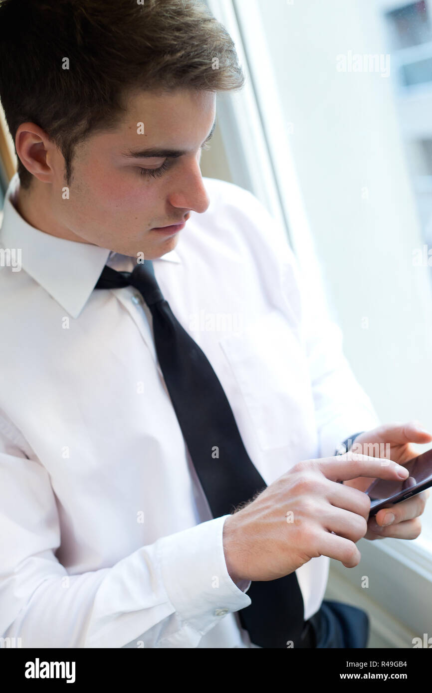 Junge Unternehmer mit seinem Handy im Büro. Stockfoto