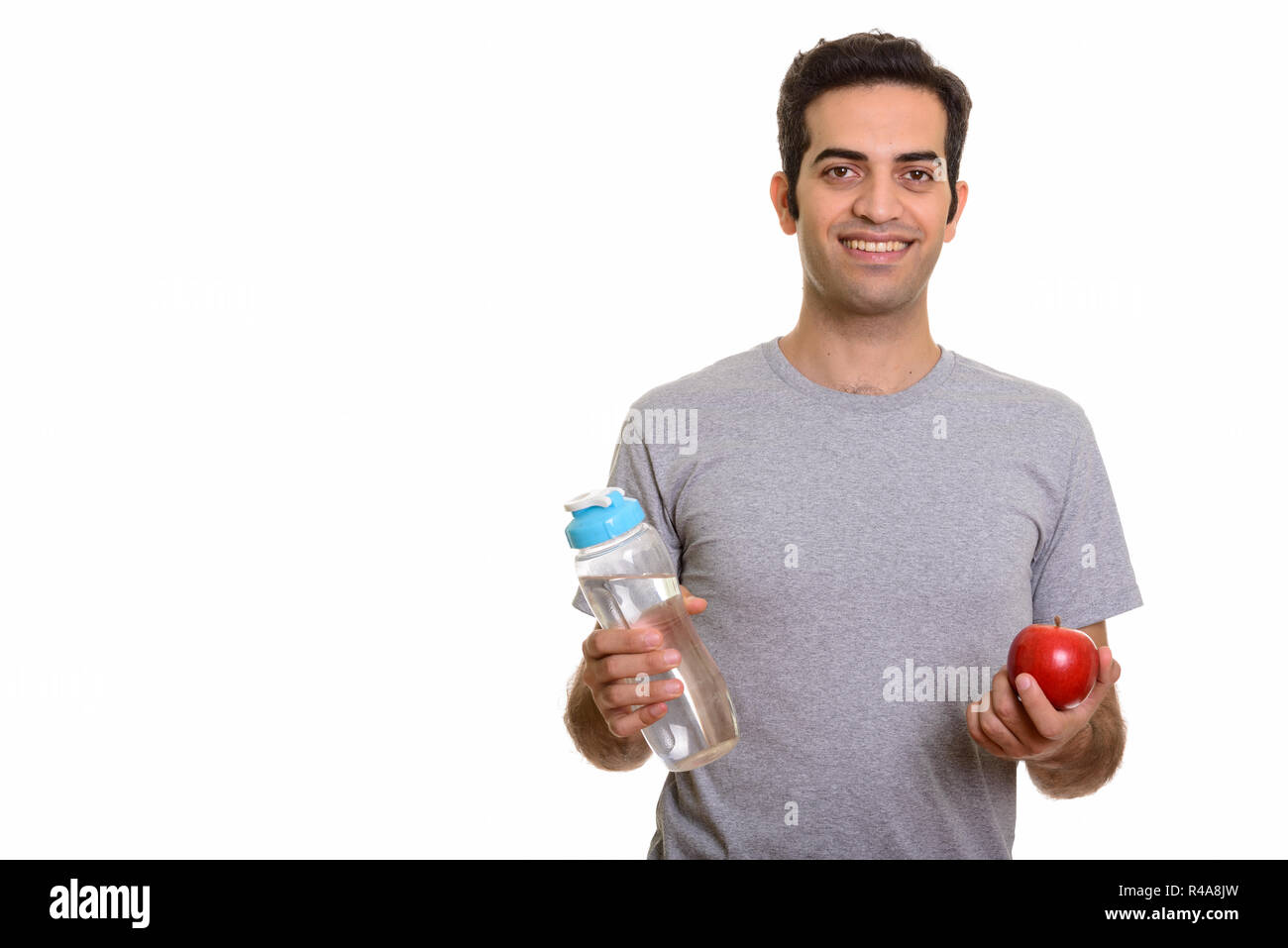 Junge glücklich Persischen Mann mit Wasserflasche und red apple bereit Stockfoto