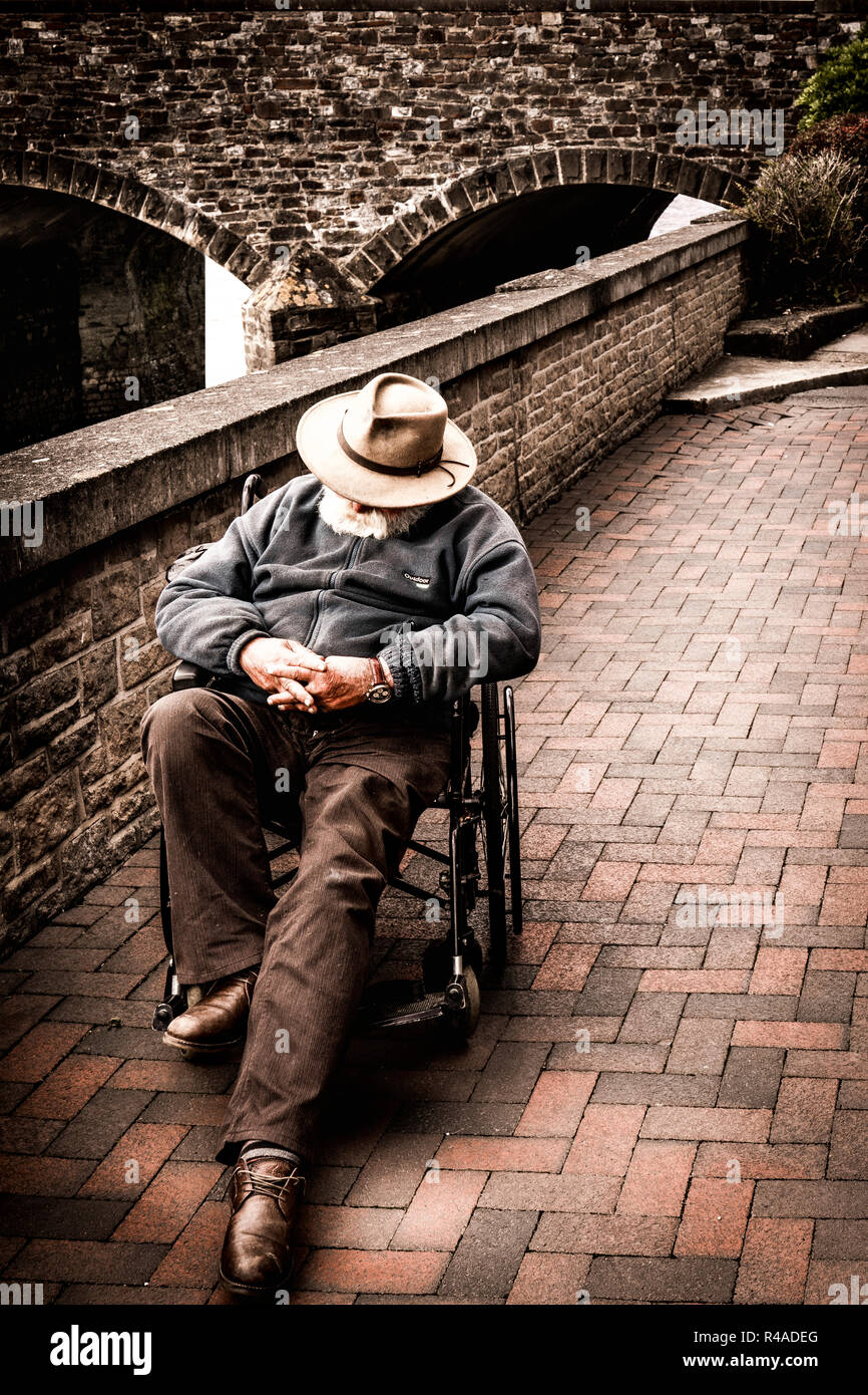 Ein Gentleman genießt ein Nickerchen am Nachmittag in seinem Rollstuhl. Stockfoto