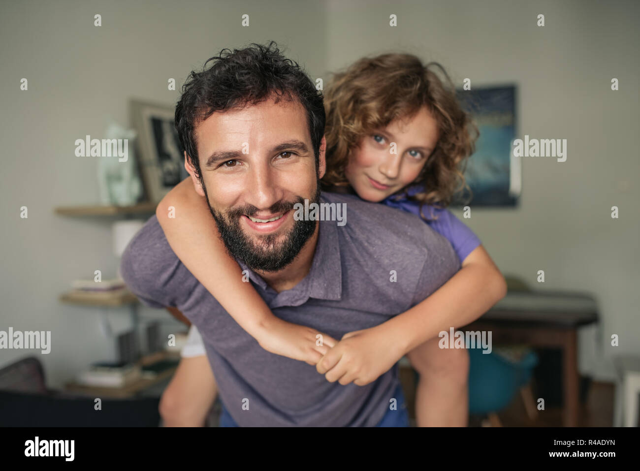 Lächelnd Vater seinen Sohn ein huckepack zu Hause Stockfoto