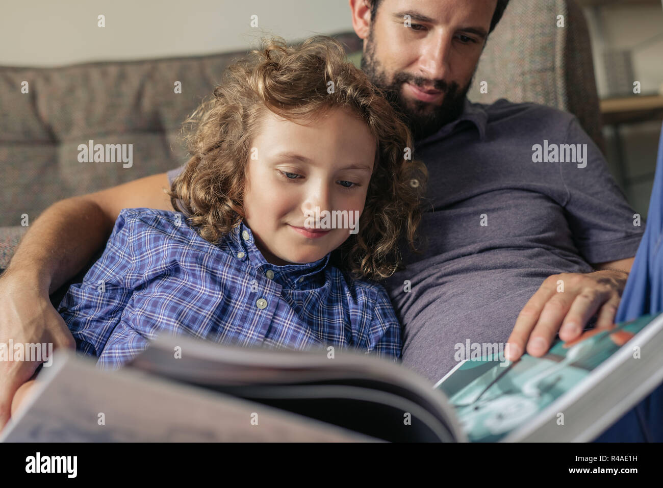 Vater und Sohn zusammen ein Buch lesen zu Hause. Stockfoto