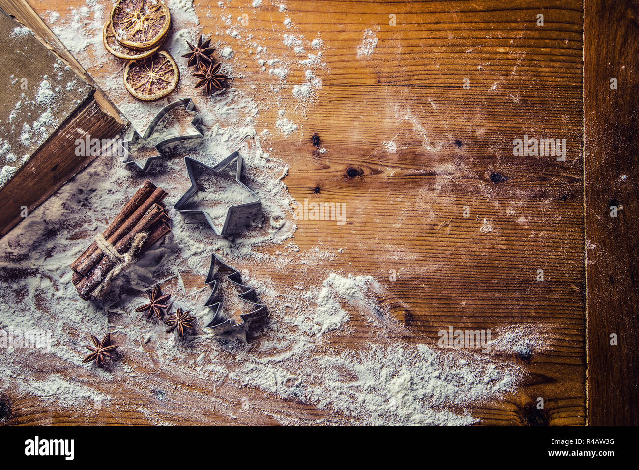 Oben auf Ansicht Bäckerei Tisch voller Weihnachten aromatischen Zutaten Sternanis Zimt Getrocknete orange Mehl Kochbuch und Ausstechformen. Stockfoto