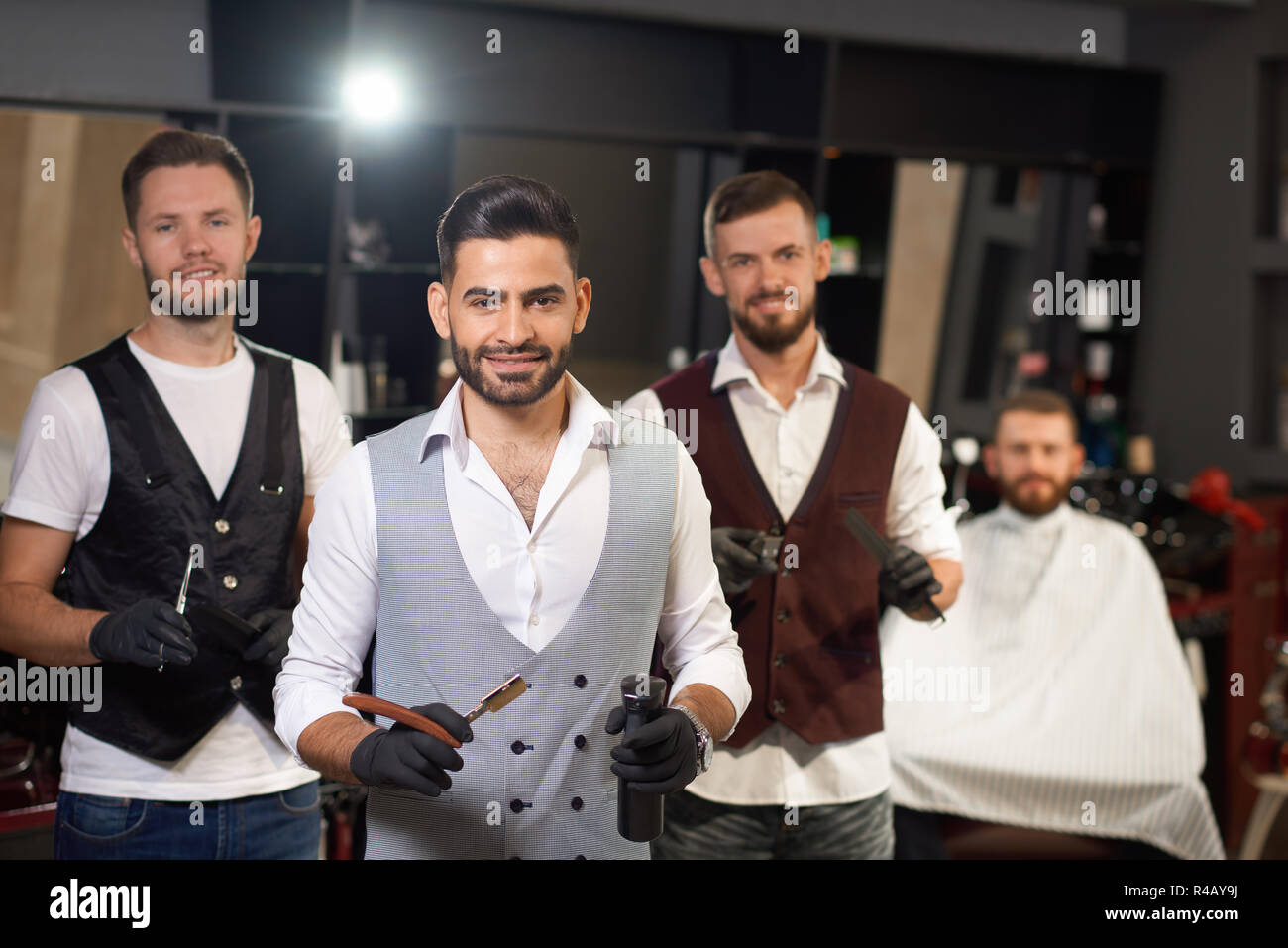 Team von professionellen Friseure stehend, auf Kamera und in der Friseur  posieren. Baum stilvolle brutale Männer halten Rasiermesser und Scheren.  Konzept der Haarschnitt und eine Rasur Stockfotografie - Alamy