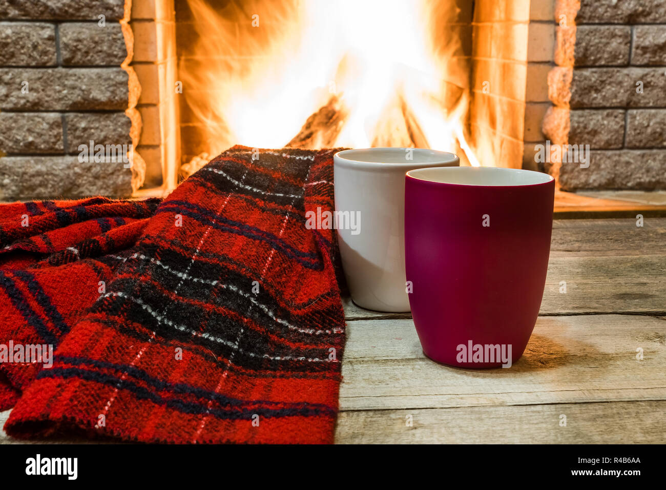 Zwei Becher mit heißem Tee und gemütlich warmen Schal in der Nähe von Kamin, im Landhaus, winter Urlaub, horizontal. Stockfoto