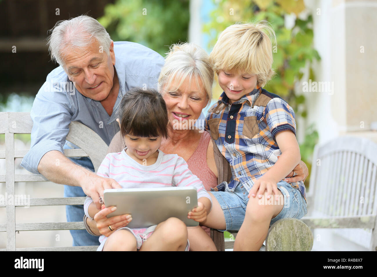 Glückliche Großeltern spielen Spiel auf Tablet mit Kindern Stockfoto
