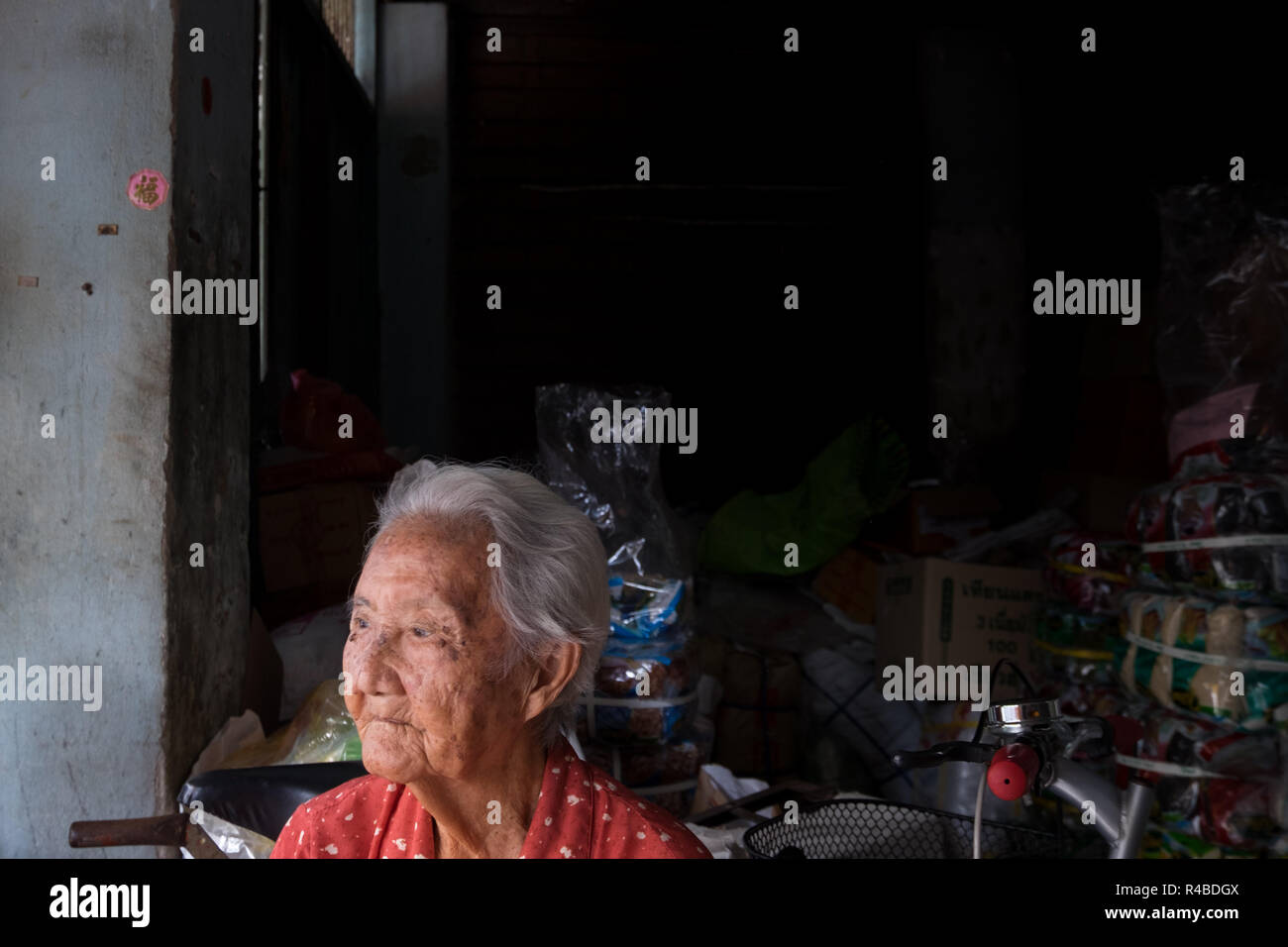 Eine alte Frau schaut aus Ihrem Shop in Hat Yai, Thailand. Stockfoto
