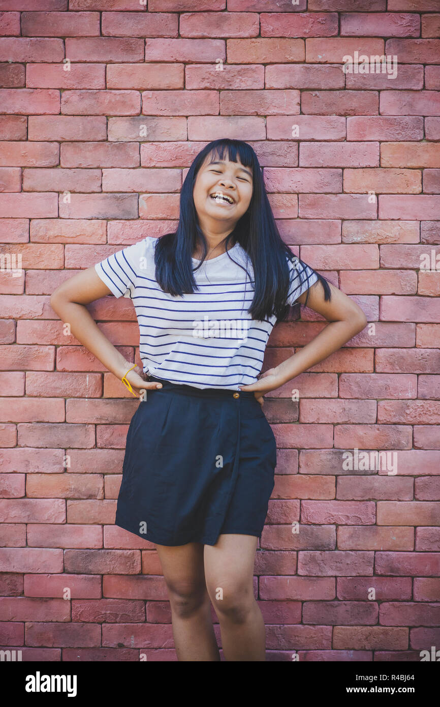 Asiatischen Teenager darstellen wie Mode Modell gegen Red brick wall Stockfoto