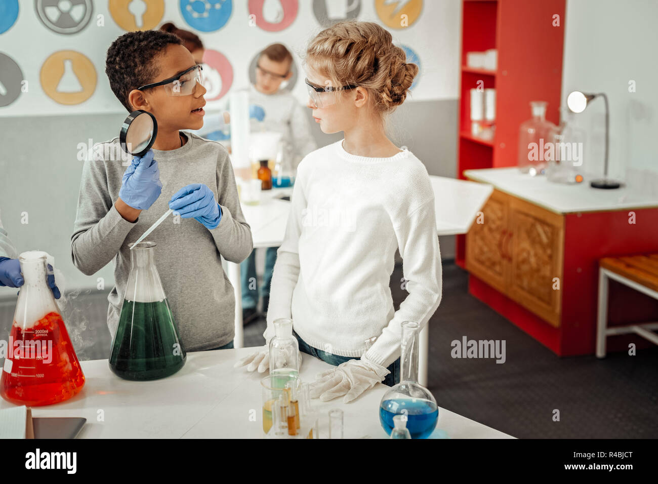 Werfen Sie einen Blick. Fröhliche afrikanischen Jungen tragen Schutzbrille beim chemischen Experimentieren Stockfoto