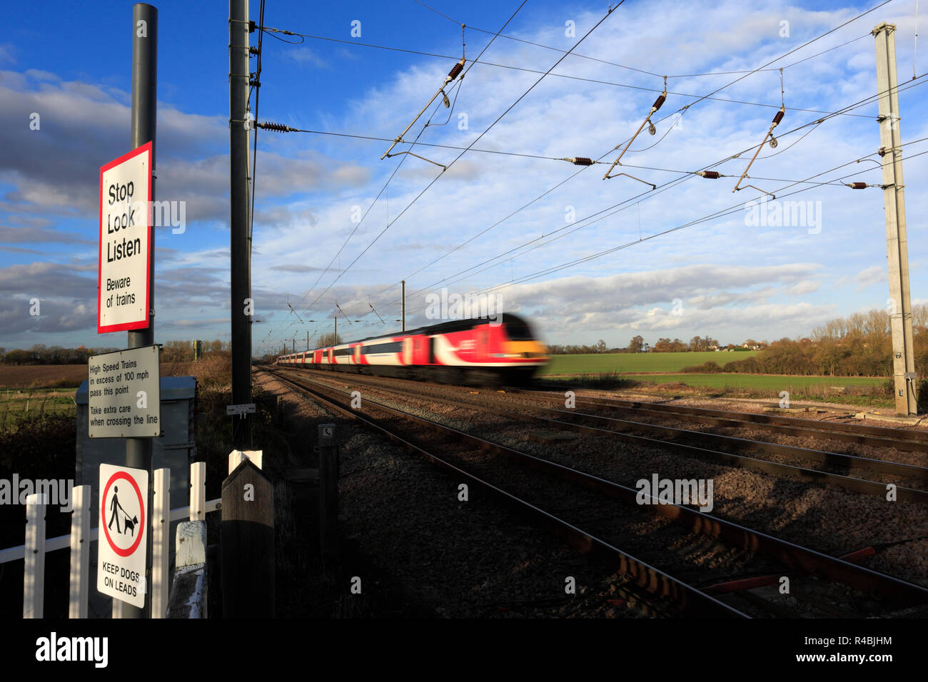 LNER Zug passiert Stop, Look, Zeichen an einem unbeschrankten Bahnübergang, Abbots Ripton Dorf, East Coast Main Line Railway, Cambridgeshire, England hören Stockfoto