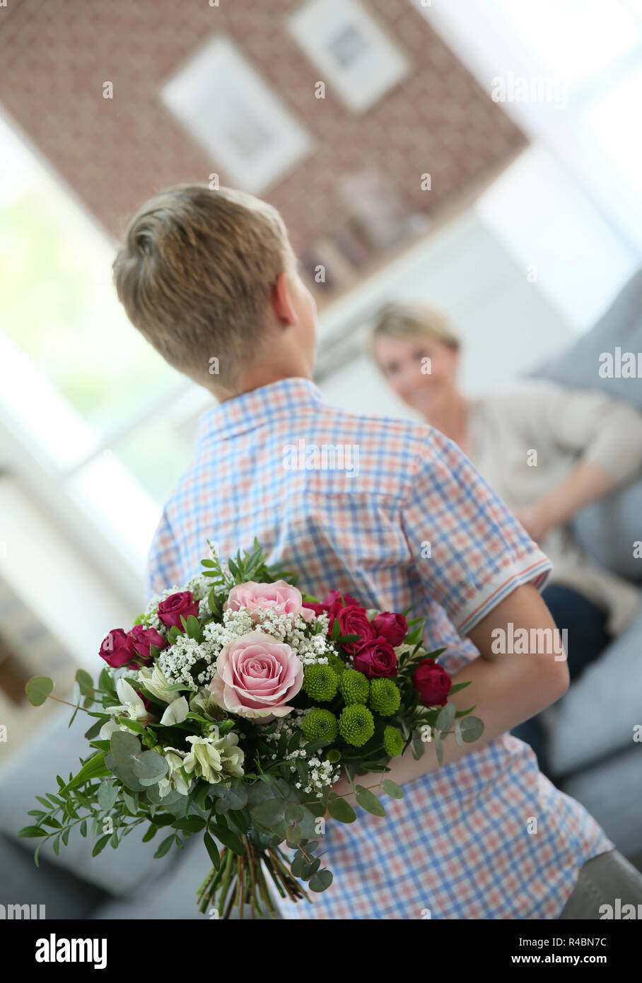 Sohn verstecken Blumenstrauß Mama am Muttertag überraschen Stockfoto