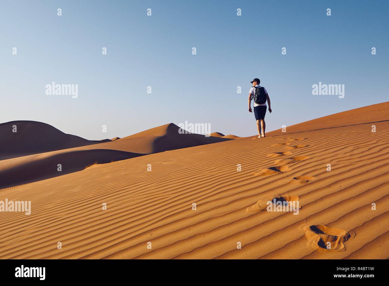 Junge Touristen mit Rucksack zu Fuß auf Sand dune. Wüste Wahiba Sands in Oman. Stockfoto