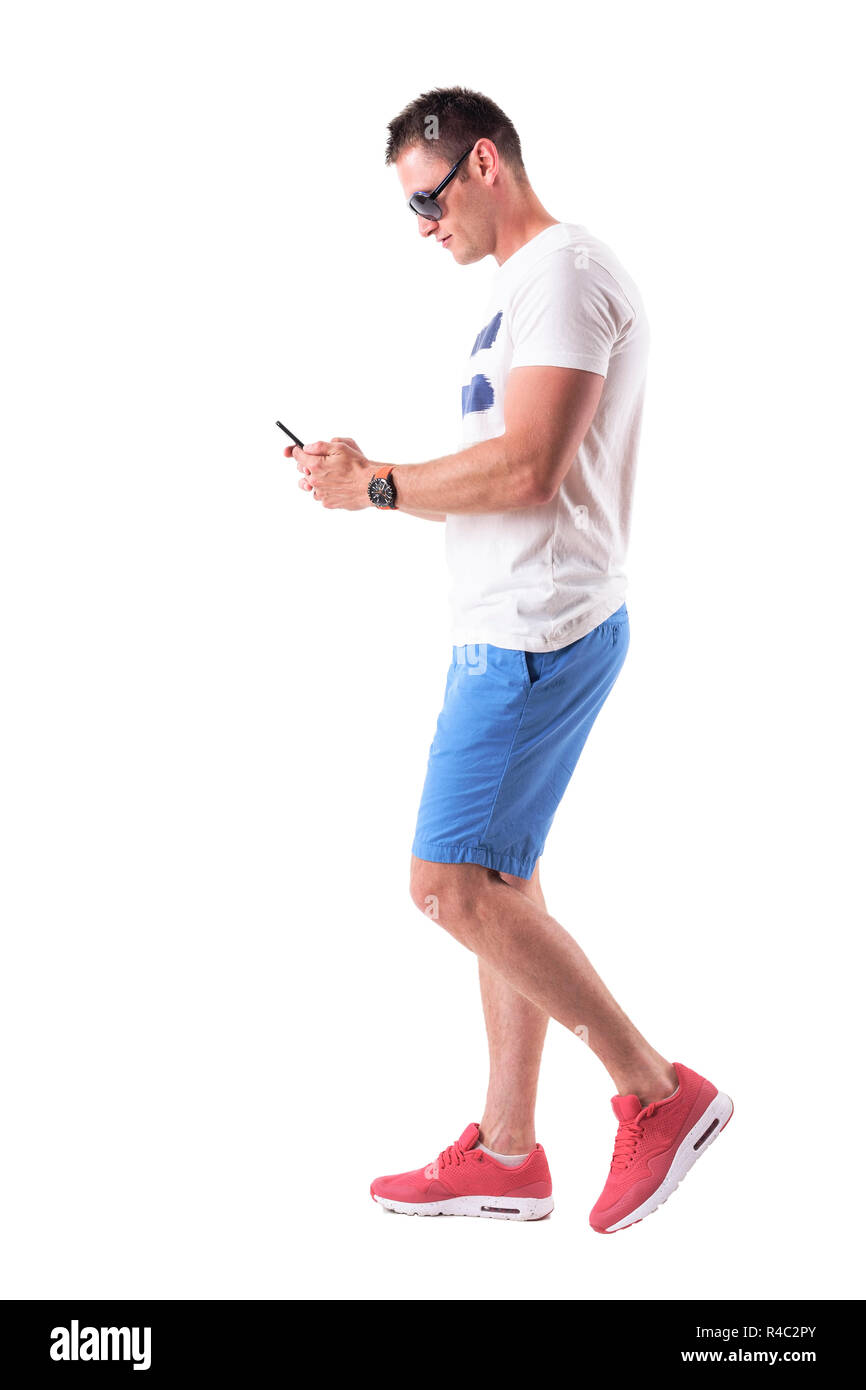 Seitenansicht des jungen Mannes im Sommer Kleidung wandern und mit Handy. Voller Körper auf weißem Hintergrund. Stockfoto