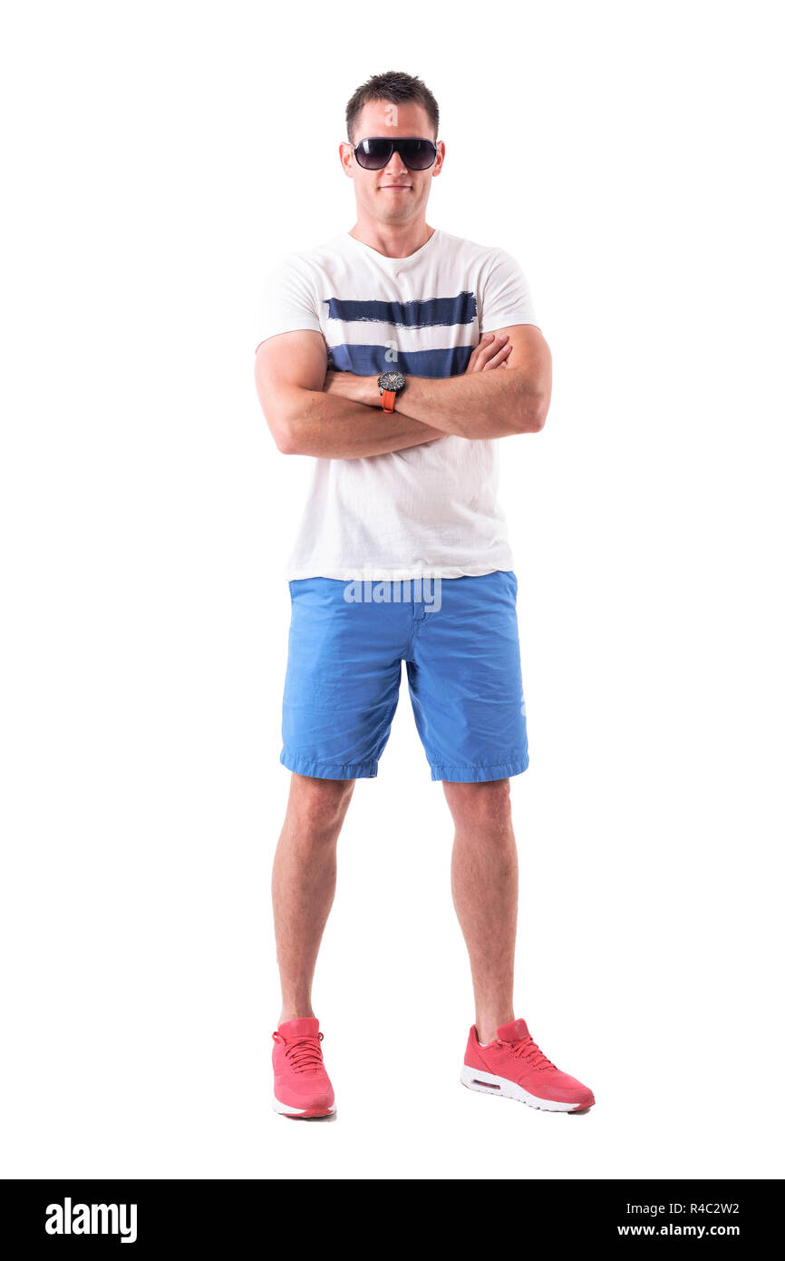 Starke athletischen Mann im Sommer Kleidung mit Sonnenbrille und verschränkten Armen. Voller Körper auf weißem Hintergrund. Stockfoto