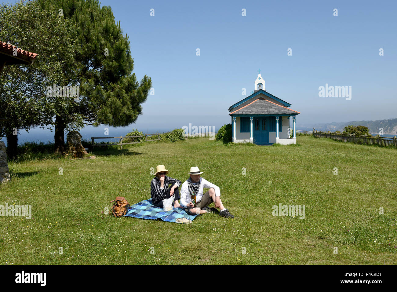 Touristen mit Picknick in der Kapelle von La Regalina, Cadavedo, Asturien, Spanien. Urlaub europa europäische spanische ländliche spanische Küste Paar. Stockfoto