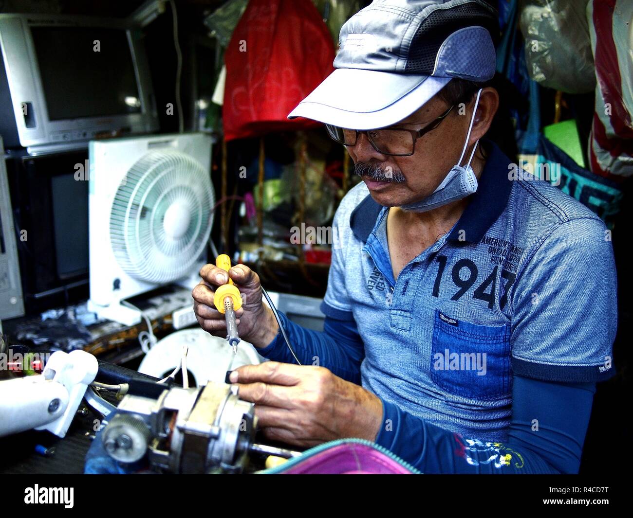 ANTIPOLO CITY, Philippinen - November 24, 2018: Ein Elektriker Reparaturen eines Haushalts los an seinem Geschäft an einer befahrenen Straße. Stockfoto