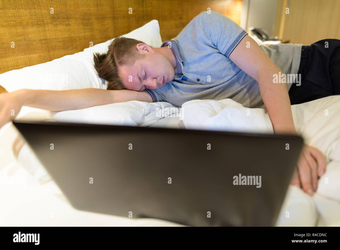 Überforderten Mann mit Laptop, während im Schlafzimmer schlafen Stockfoto