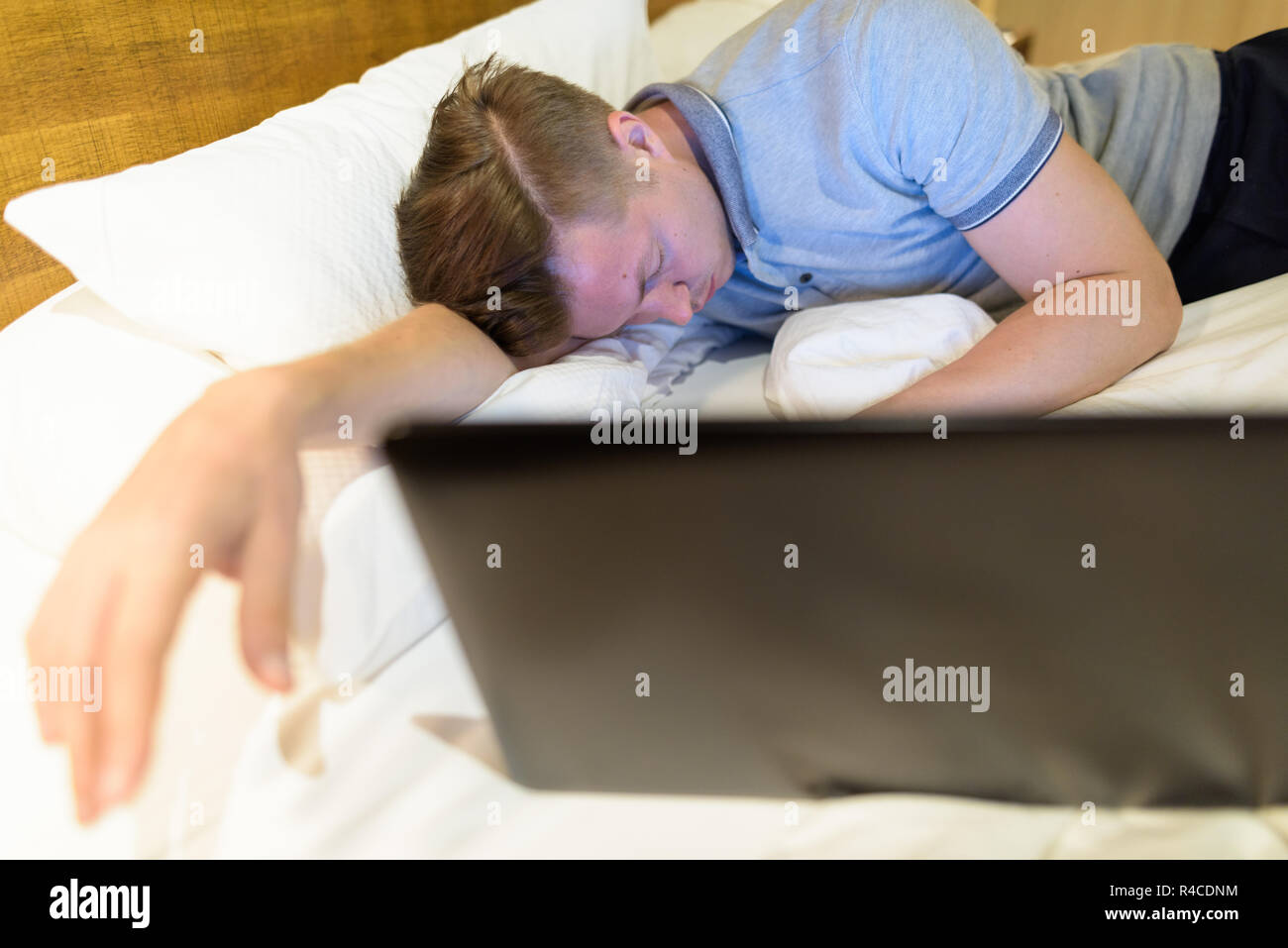 Überforderten Mann mit Laptop, während im Schlafzimmer schlafen Stockfoto